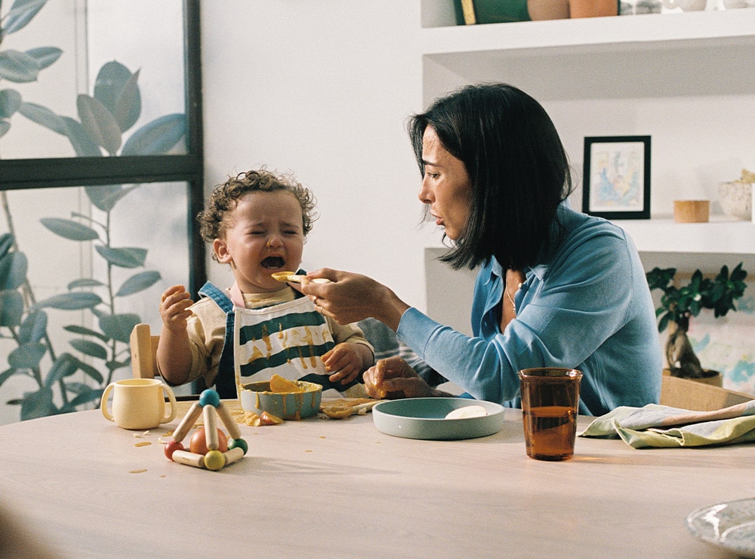 Bebé llorando y madre alimentando